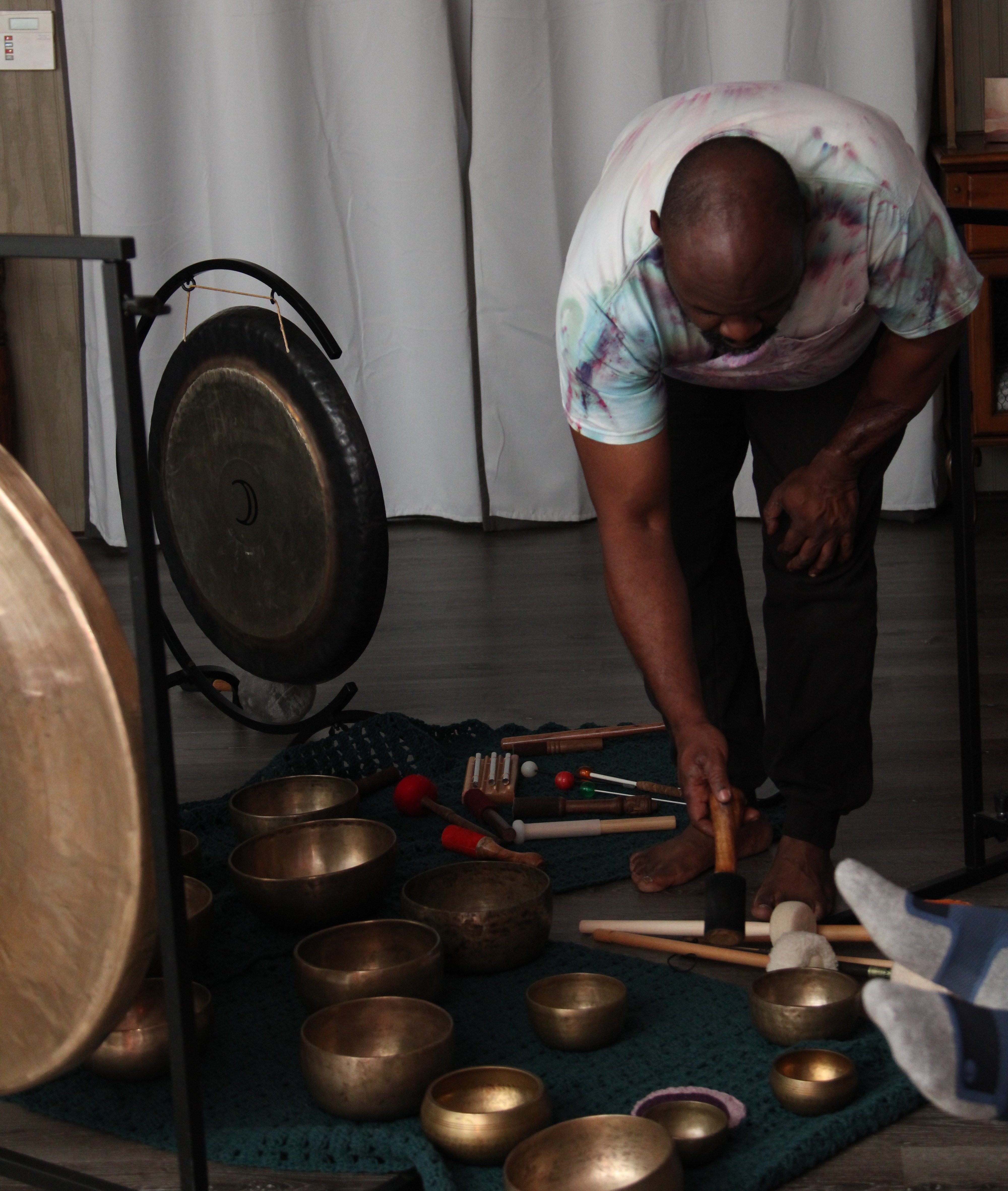 Practitioner setting up gongs and singing bowls for a sound bath